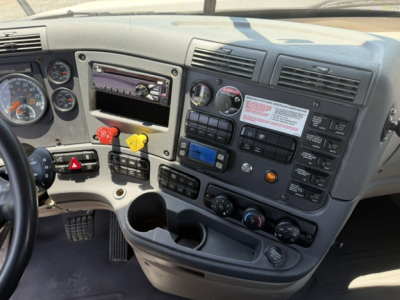 Freightliner Cascadia truck cab interior dashboard showing gauges, steering wheel, control switches, and radio area.