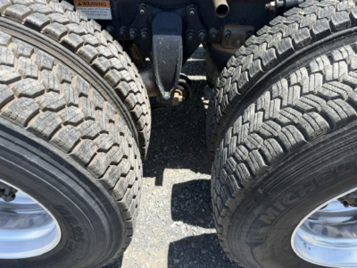 Freightliner Cascadia chassis showing dual rear axles and tires with visible suspension components.