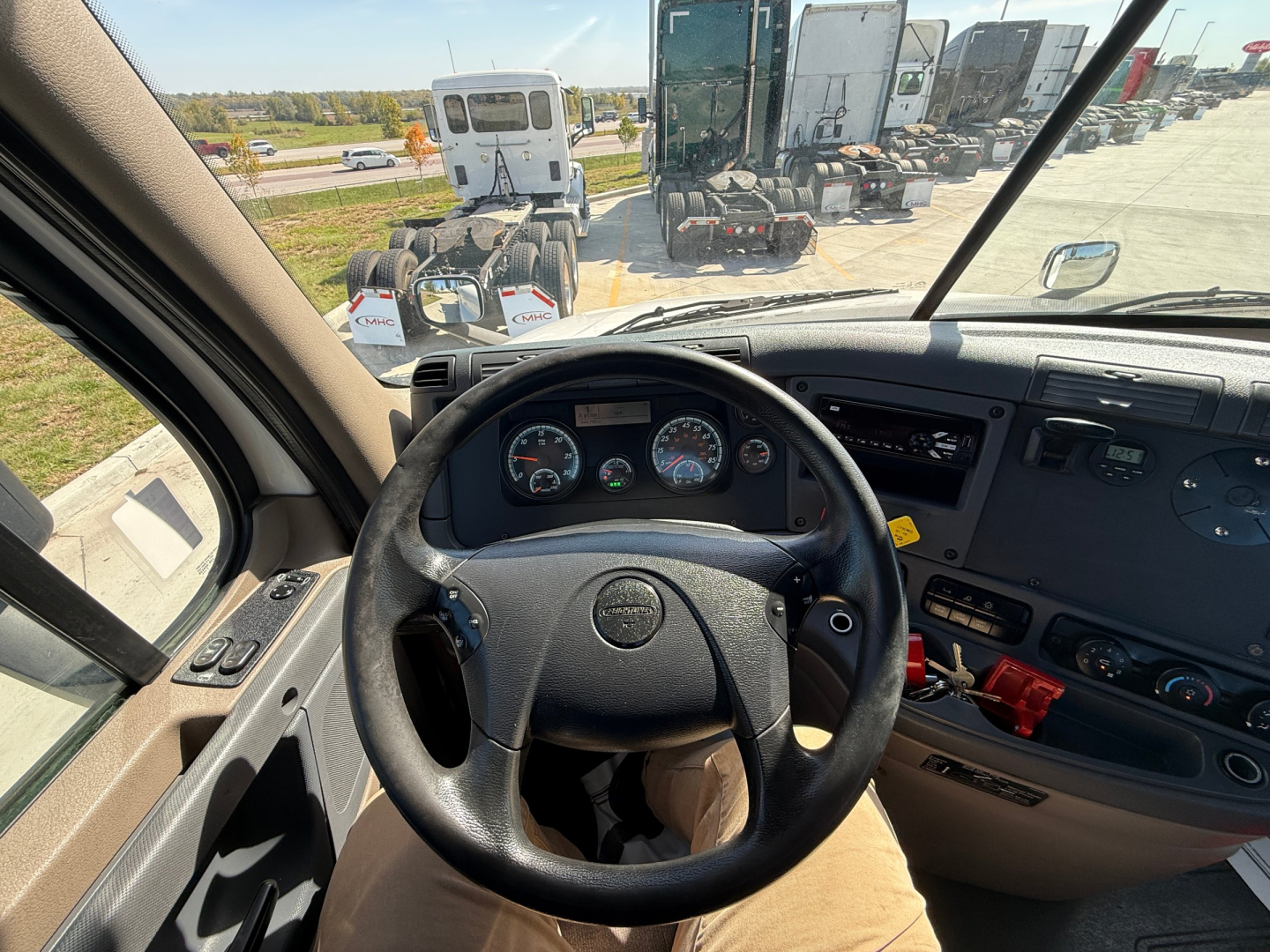 Cab interior of Freightliner CA12564DC showing steering wheel, dashboard gauges, and center console.