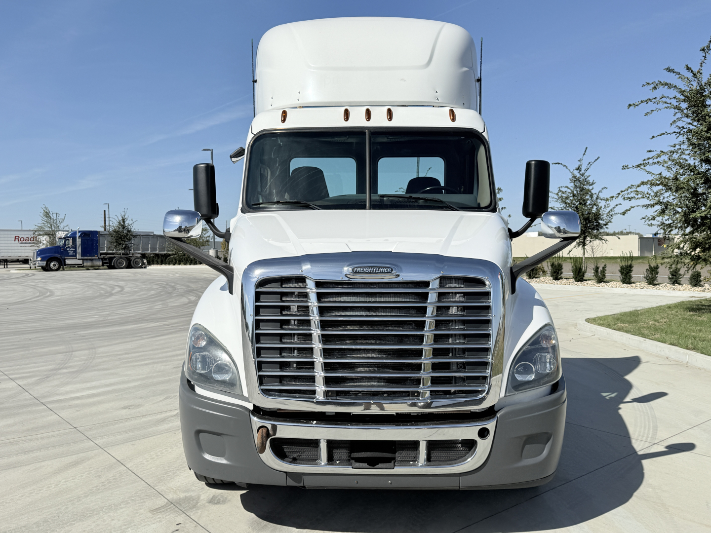 Freightliner CA12564DC front view showing bold chrome grille, large bumper, and rectangular headlights. No text visible on windshield or bumper.