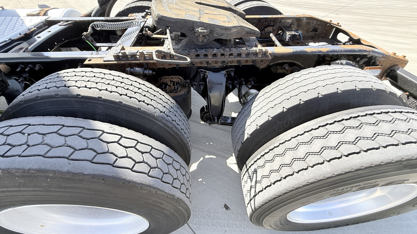 Dual rear tractor tires and undercarriage of a Freightliner CA12564DC conventional daycab showing chassis and wheel hubs.