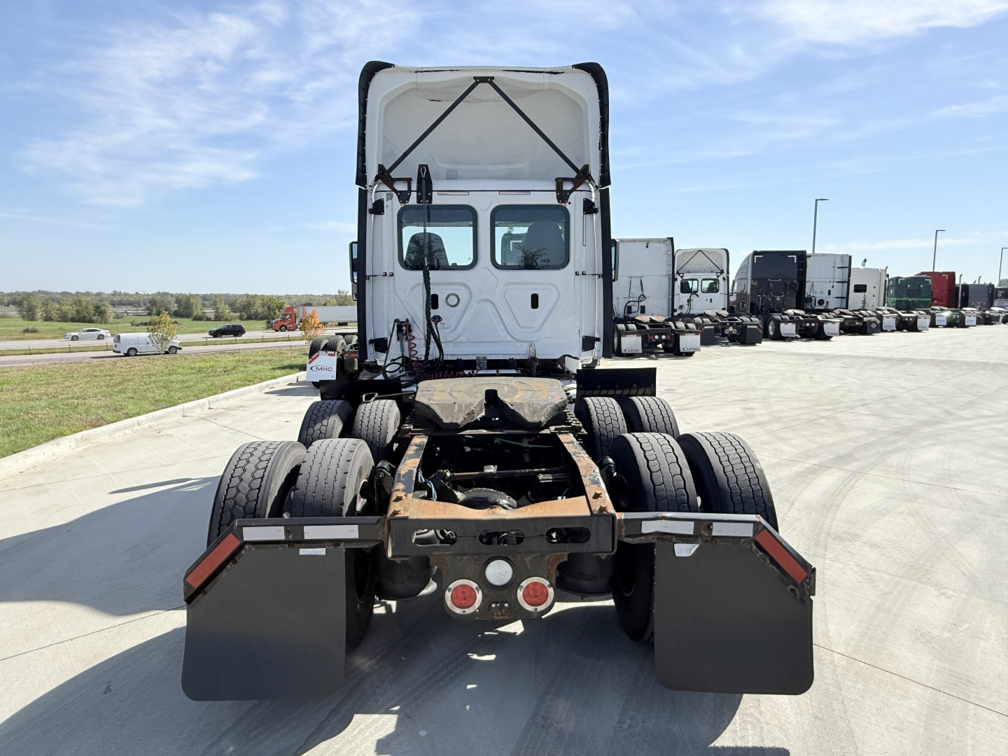 Rear view of a Freightliner tractor with fifth wheel missing, showing dual rear axles and mud flaps.
