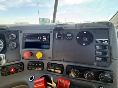 Freightliner cab interior dashboard showing steering column, gauges, ignition, knobs, and control panels.
