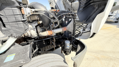 Truck engine bay of a 2018 Freightliner CA12564DC showing engine components, hoses, and hydraulic lines.