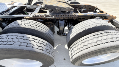 Dual rear tractor tires and undercarriage of a Freightliner CA12564DC conventional daycab showing chassis and wheel hubs.