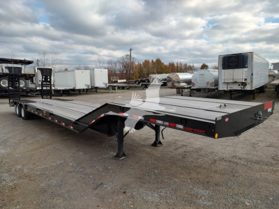 Low-angle view of a Dorsey LB35-33CS drop deck trailer showing gooseneck and support legs, black with red reflectors, parked in a lot.