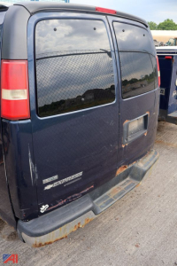 Chevrolet Express van rear view showing cargo doors, window tint, and bumper with rust; model badge 'EXPRESS' and 'VAN' visible on lower left rear; partial tail light and rear door seam.