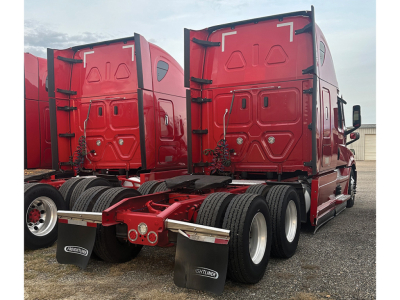 Freightliner Cascadia126 tractor rear view showing dual rear axles and red sleeper cab with matching red mud flaps.