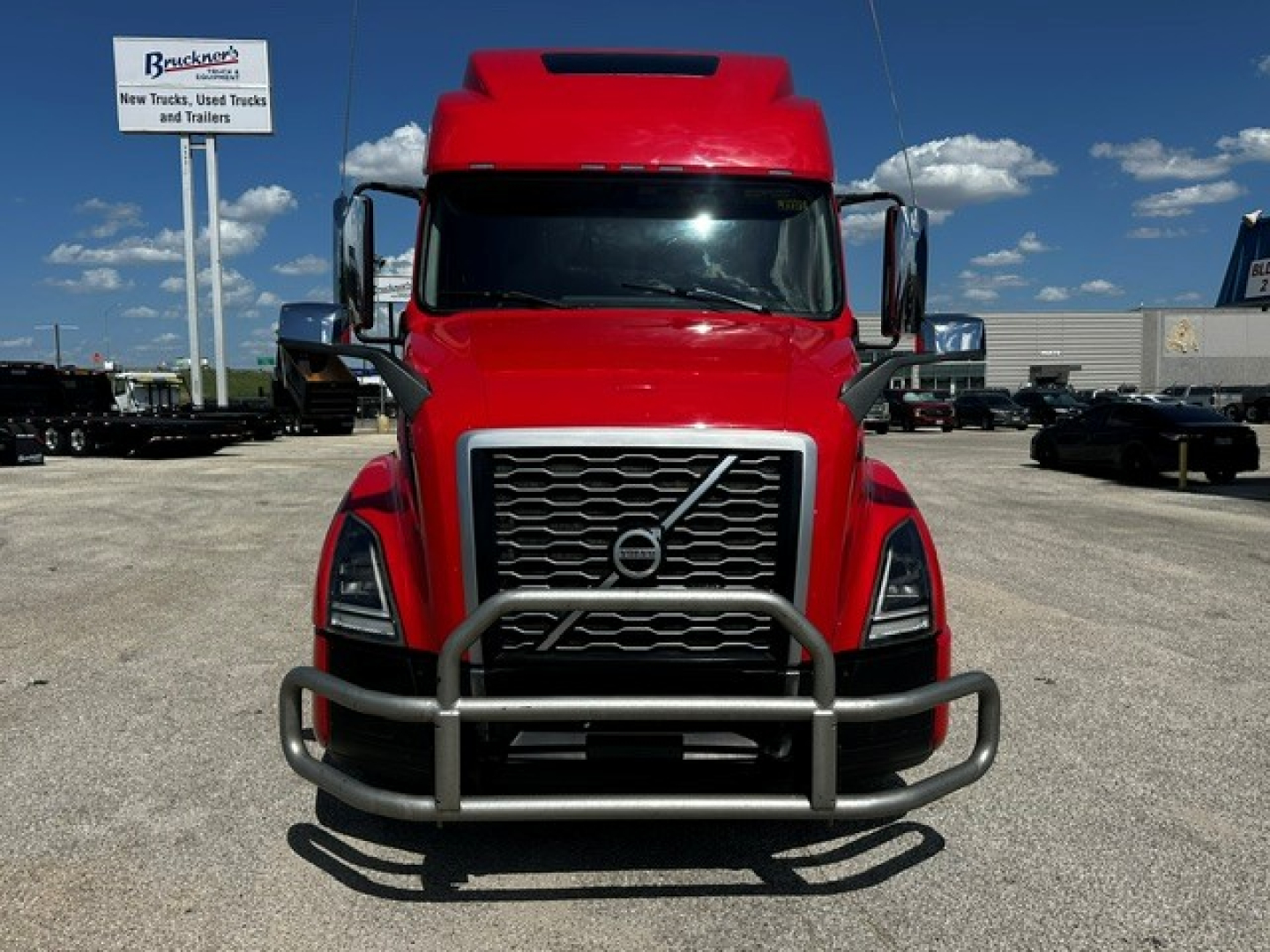 Volvo VNL64T860 truck front view with bull guard, red cab, large grille, in a dealership lot.