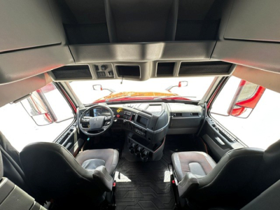Volvo VNL64T860 truck cabin interior view with steering wheel, dashboard, and two front seats.