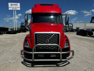 Volvo VNL64T860 truck front view with bull guard, red cab, large grille, in a dealership lot.