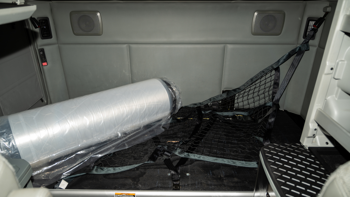 Kenworth T680 interior cargo area showing a rolled privacy curtain and netting, with side panels and ceiling speakers visible.