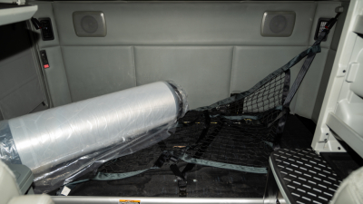 Kenworth T680 interior cargo area showing a rolled privacy curtain and netting, with side panels and ceiling speakers visible.