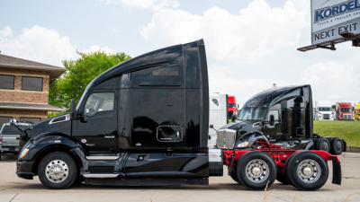 Kenworth T680 tractor in-service cab and chassis view showing glossy black exterior, side mirror, aerodynamic sleeper, and dual rear axles.