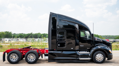 Truck cab side profile of a 2019 Kenworth T680 with black paint and chrome wheels, part of a sleeper tractor-hood configuration.