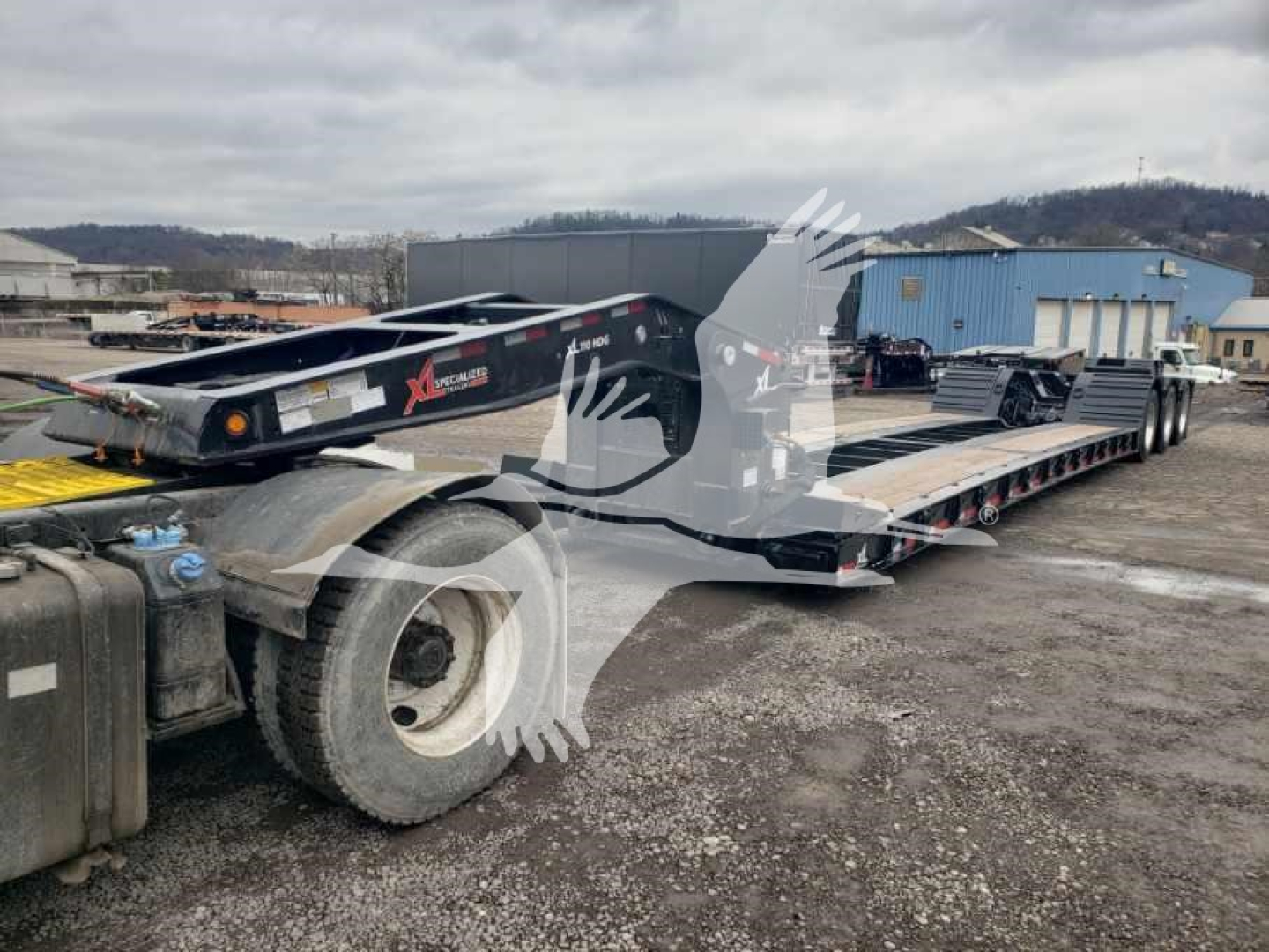 XL Specialized 55 Ton lowboy trailer showing 15" deck height with wheel covers and multiple axles.