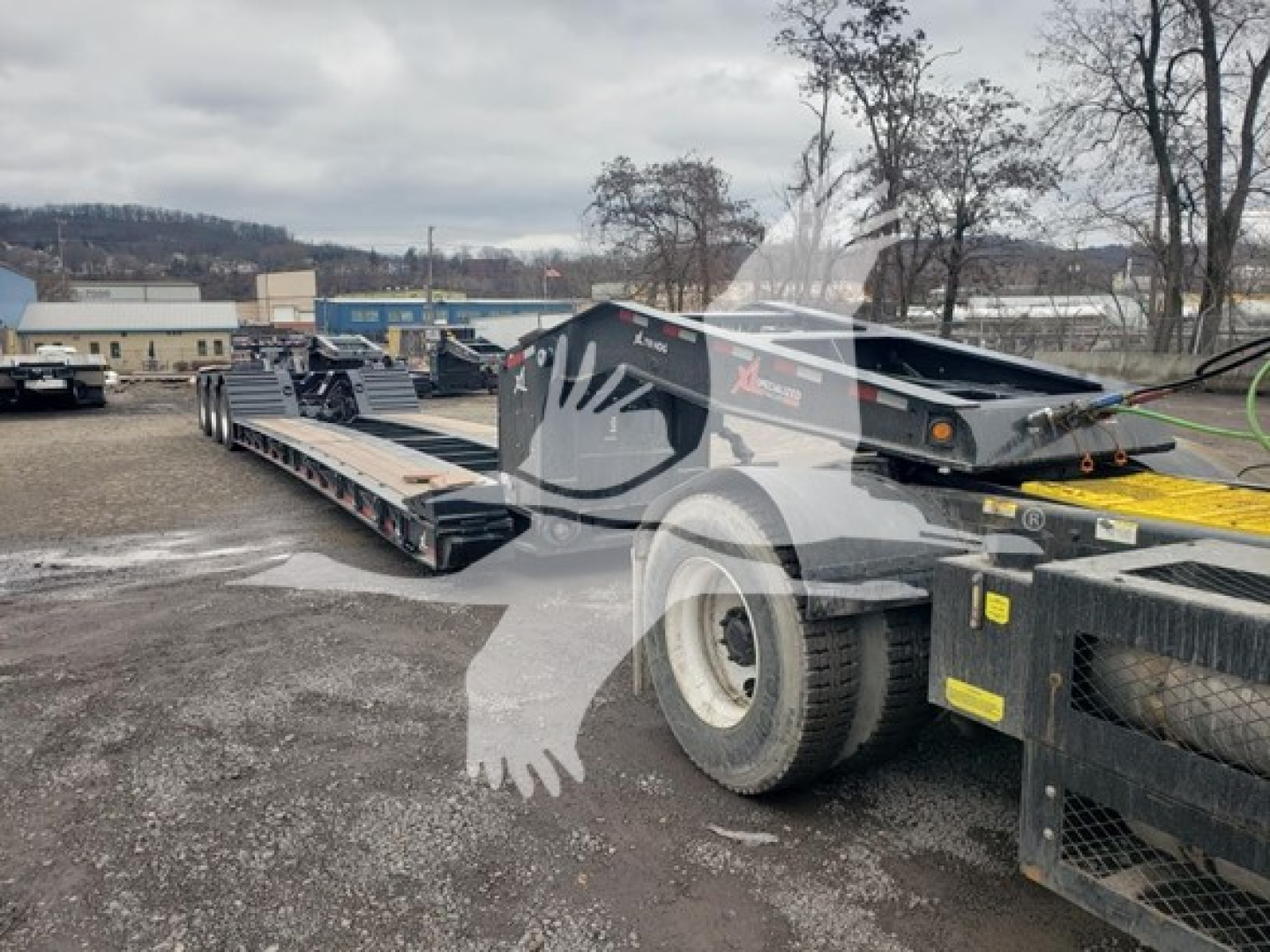 Lowboy trailer with 55-tonXL Specialized tag showing extended flatbed, dual axles, hydraulic ramps in a yard.