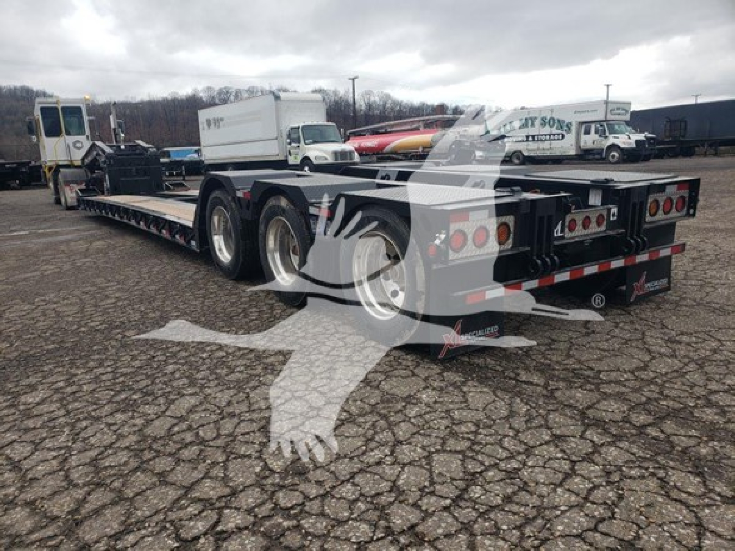 Lowboy trailer showing dual-axle deck with rear lights and heavy-duty frame, 55-ton capacity, with tire set and tag tail; rear view and Canadian-style plate area visible.