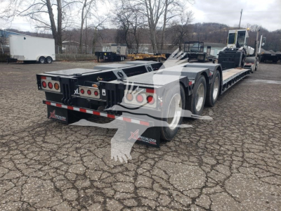 XL Specialized 55 Ton 15" Deck Height lowboy trailer showing dual rear ramps and wheel covers with multiple axles and taillights.