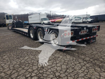 Lowboy trailer showing dual-axle deck with rear lights and heavy-duty frame, 55-ton capacity, with tire set and tag tail; rear view and Canadian-style plate area visible.