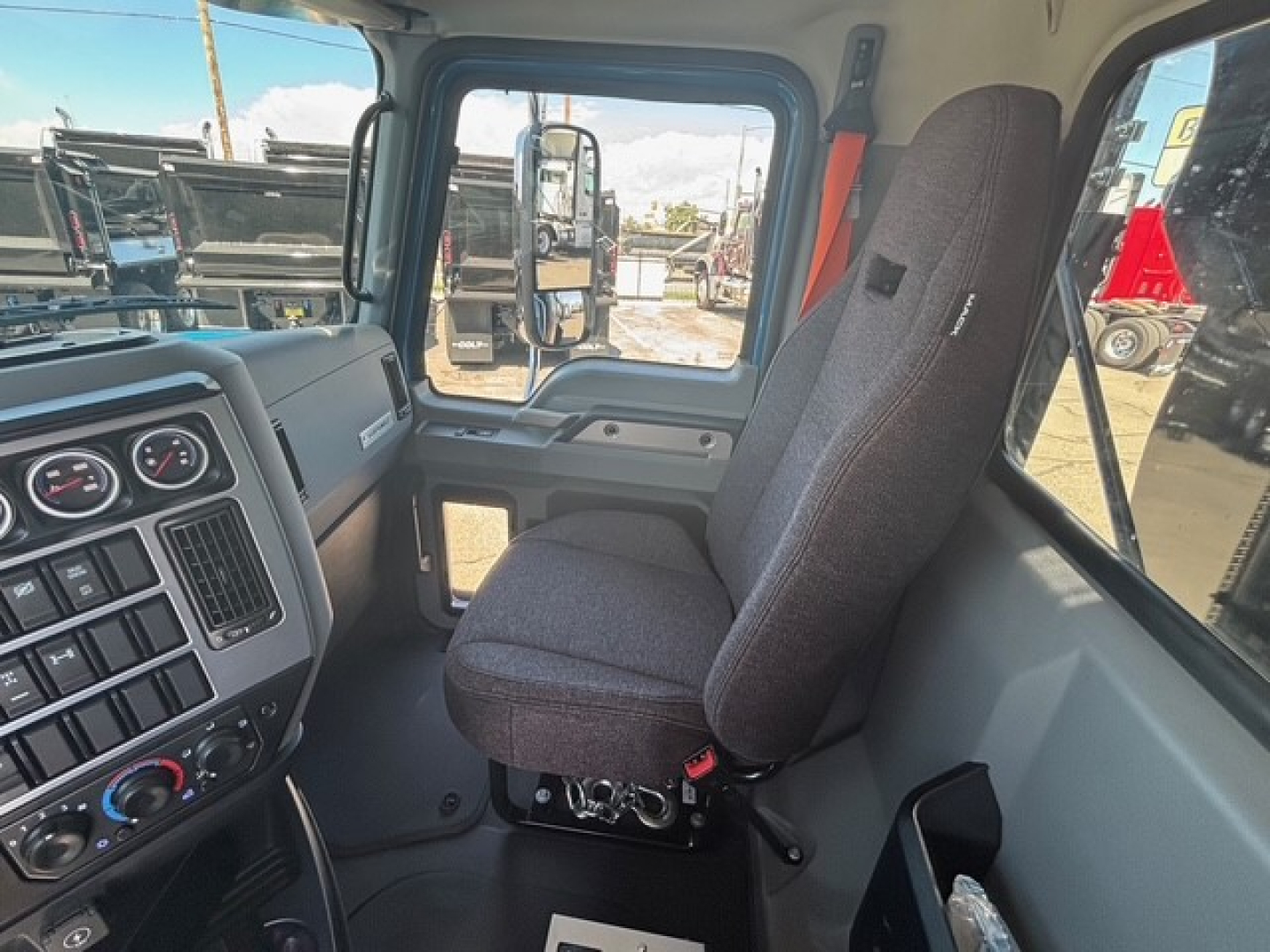 Vehicle cab interior of a Mack GR64F dump truck showing driver's seat and dashboard with gauges and control panel.