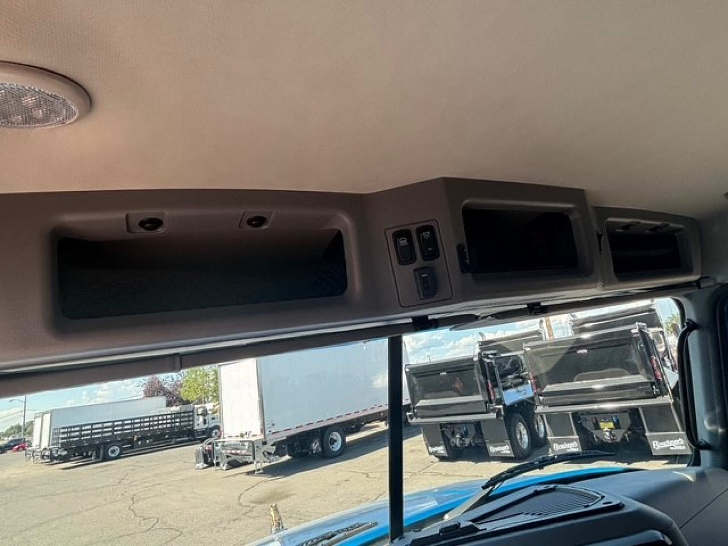 Cab interior of a 2026 Mack GR64F showing overhead dash with control panel and storage compartments.