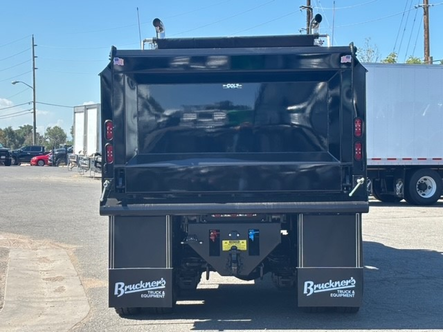 Dump truck bed of a 2026 Mack GR64F showing rear view with hydraulic dump body and mud flaps labeled Bruckner Equipment. Visible VIN, stock tag area and rear lights.