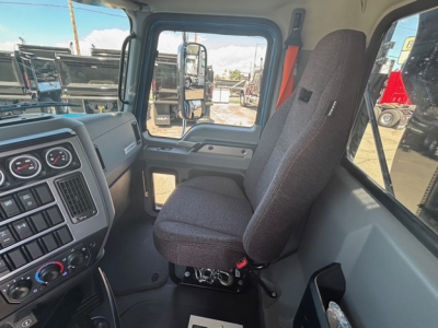 Vehicle cab interior of a Mack GR64F dump truck showing driver's seat and dashboard with gauges and control panel.