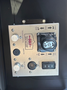 Control panel with multiple labels: 'PTO', 'HOLD', 'RANGE', 'CLEANER', 'TANK CONTROL', 'LIGHTS', 'IGNITION' and a large round knob; shows a small 'DOCK' style sticker and a blue switch labeled 'ON/OFF' and 'OFF/ON' with text around.