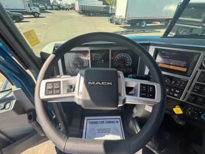 Mack GR64F truck interior showing steering wheel with MACK logo, dashboard gauges, and infotainment screen.