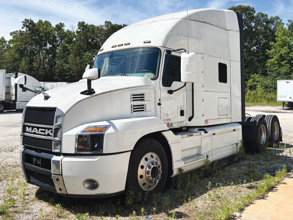 Mack Anthem truck in a lot showing front and driver side with sleeper cab and white paint.