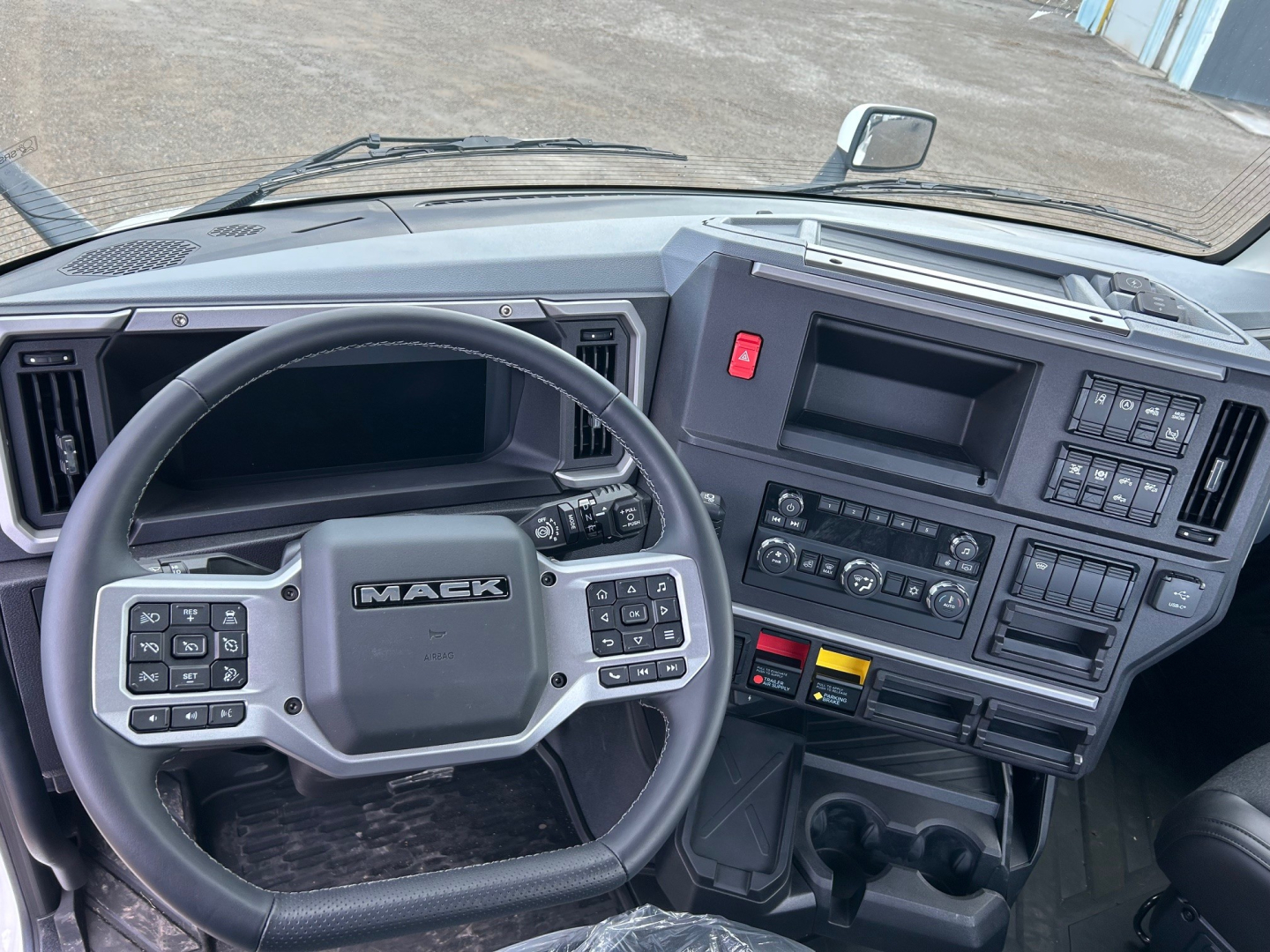 Mack PR64T truck interior dashboard and steering wheel showing control panels, gauges, and center console.