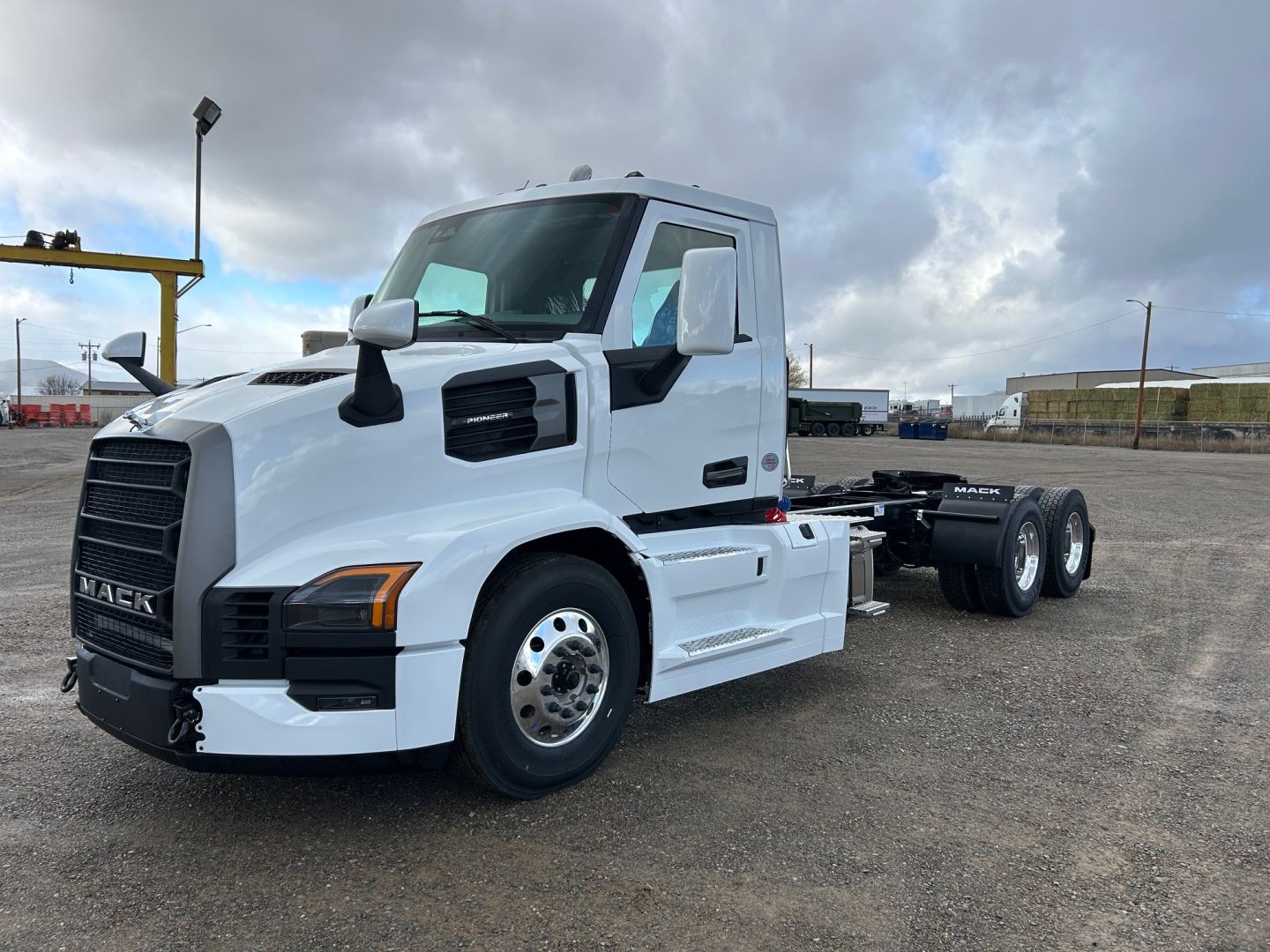 White Mack PR64T truck chassis side view showing front grille with Mack emblem, cab with black mirrors, and dual rear axles; no visible text except truck styling.