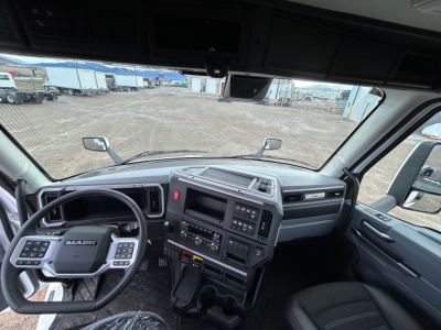 Mack PR64T cab interior showing steering wheel with Mack badge, dashboard controls, center stack, gear shifter, driver and passenger seats.