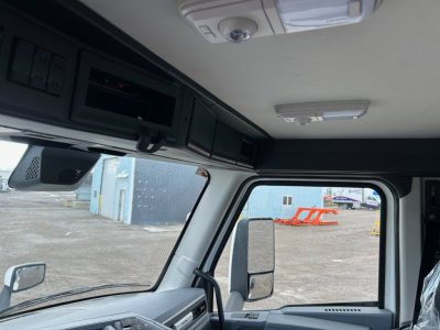 Cab interior of a 2026 Mack PR64T truck showing overhead console, sun visor, ceiling light, and driver side window with mirror.