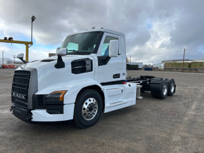 White Mack PR64T truck chassis side view showing front grille with Mack emblem, cab with black mirrors, and dual rear axles; no visible text except truck styling.