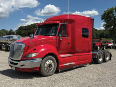 International ProStar 122 Premium red sleeper cab tractor front-left view with chrome grille and dual rear axles.
