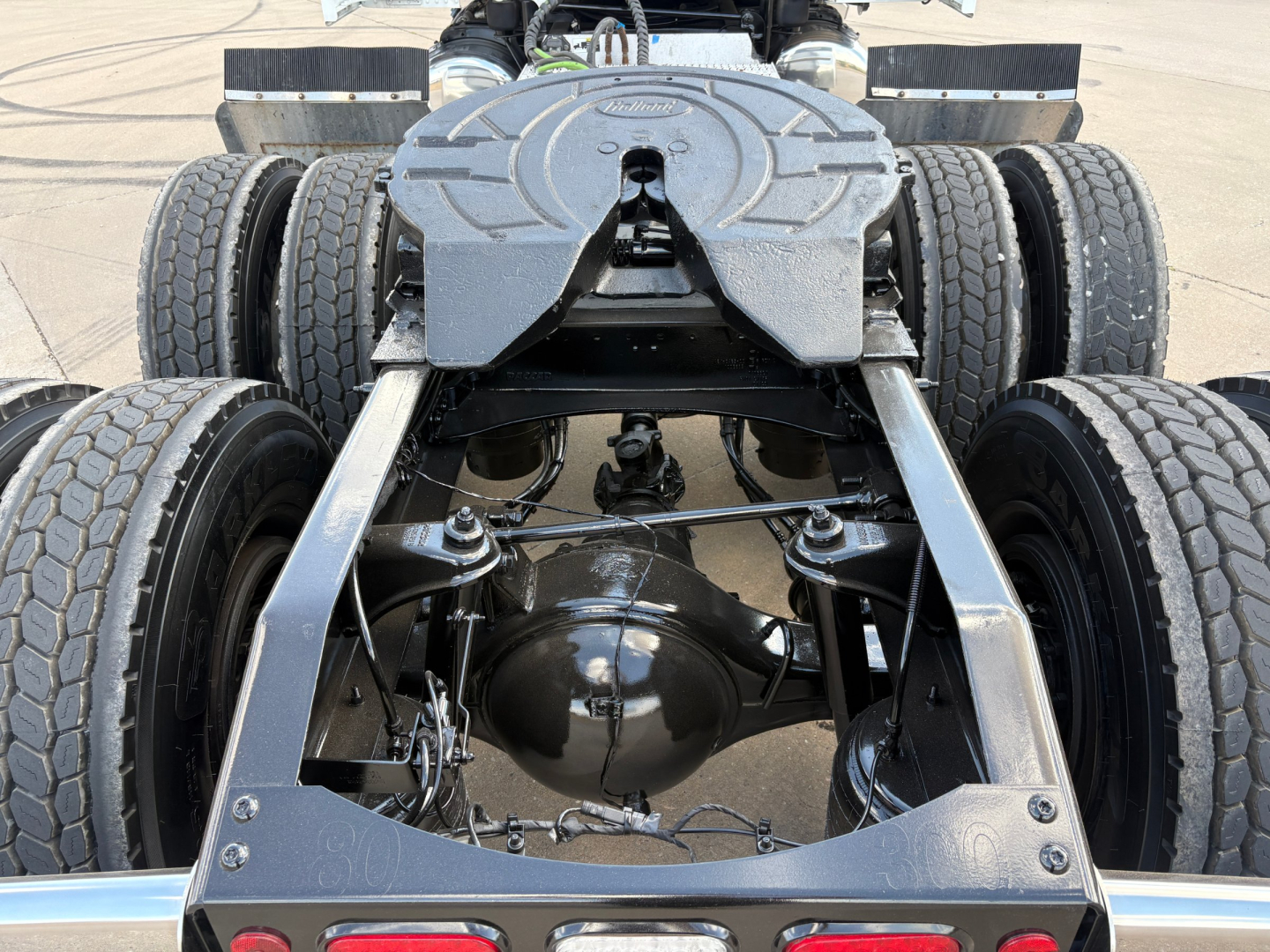 Peterbilt 579 chassis view showing rear axle differential, suspension, and fuel tanks from below; twin rear dual tires on both sides with alloy frame.