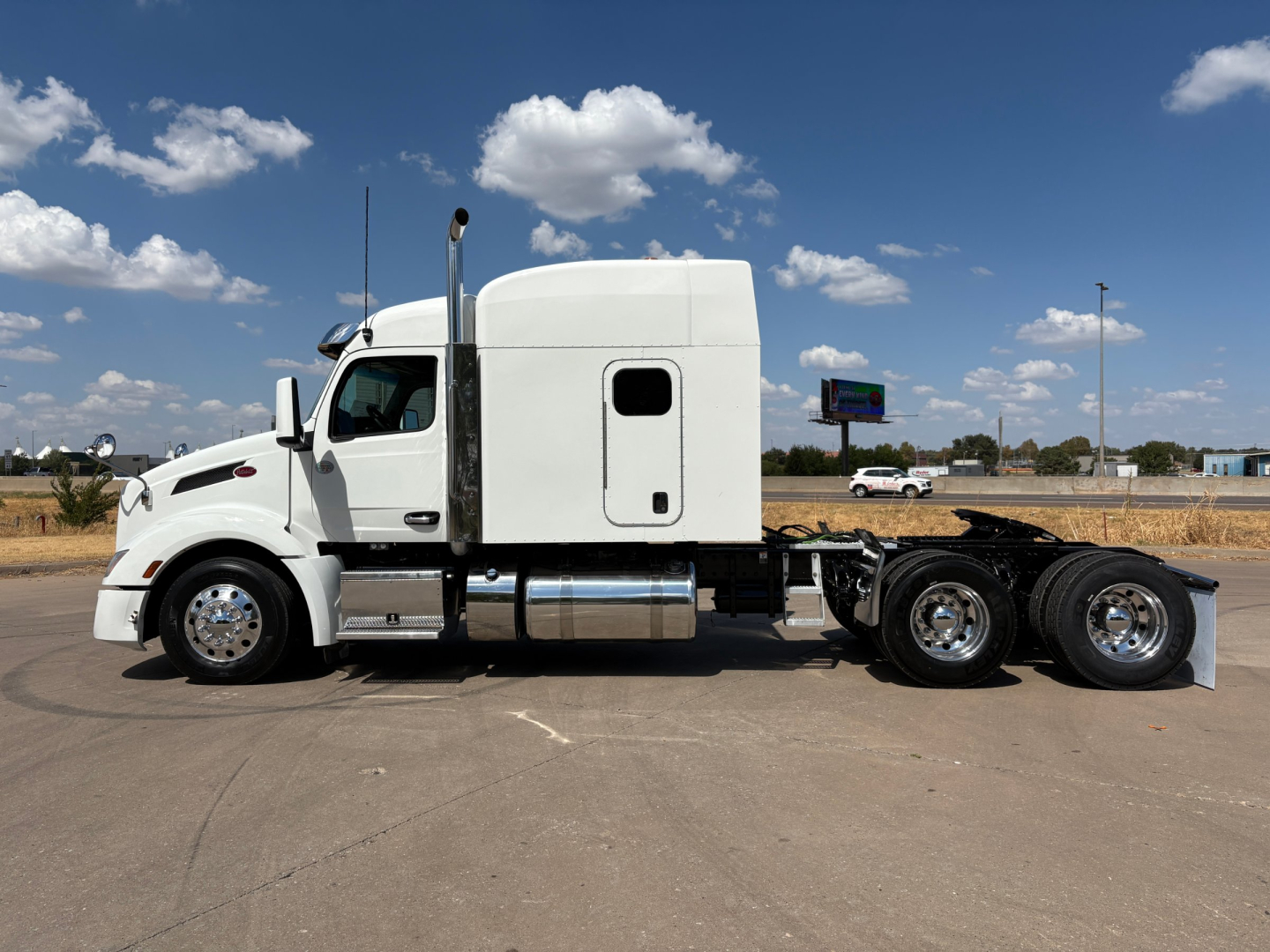 Peterbilt 579 Conventional Sleeper truck in side profile showing white cab and rear chassis with dual rear axles.