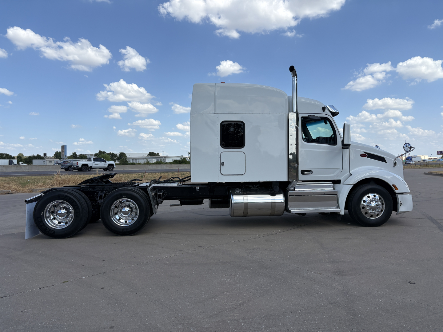 Peterbilt 579 conventional sleeper truck side view showing chrome fuel tanks and dual rear axles.