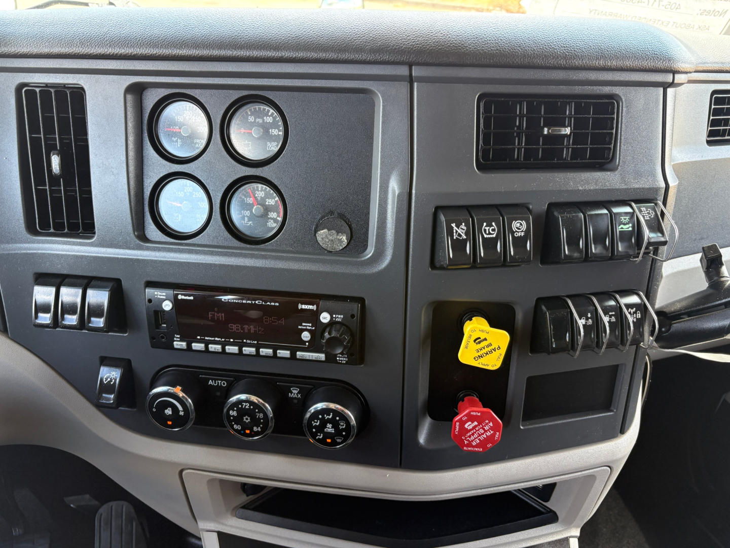 Peterbilt 579 dashboard and instrument cluster with gauges, control switches, and yellow and red keys in ignition area.