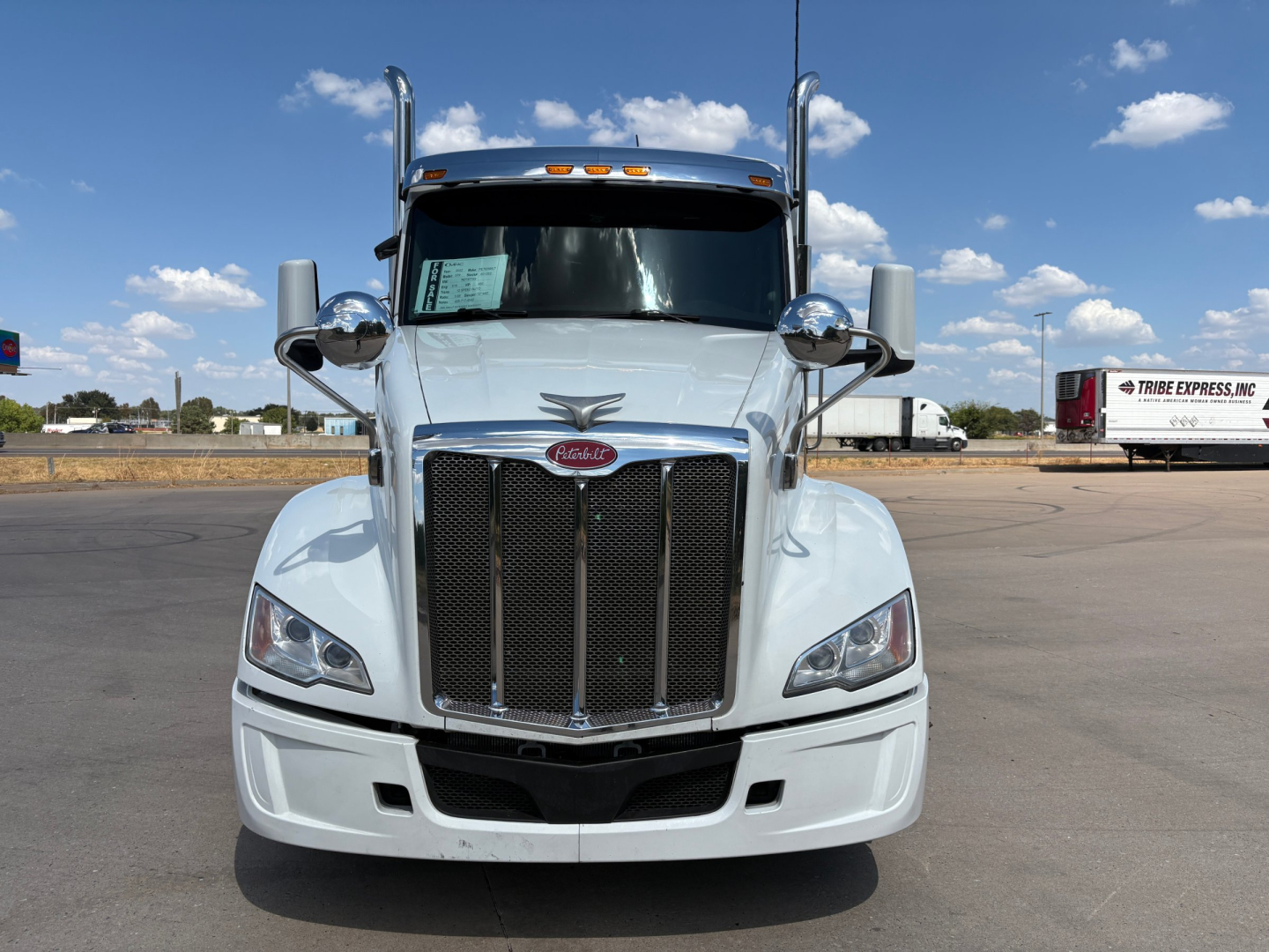 Peterbilt 579 tractor-view front showing large grille, headlights, side mirrors, and Peterbilt emblem; white exterior.