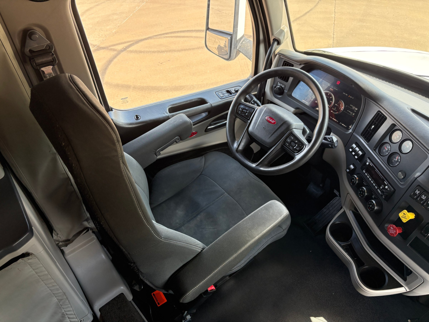 Peterbilt 579 truck cab interior showing steering wheel, dashboard gauges, and driver seat view.