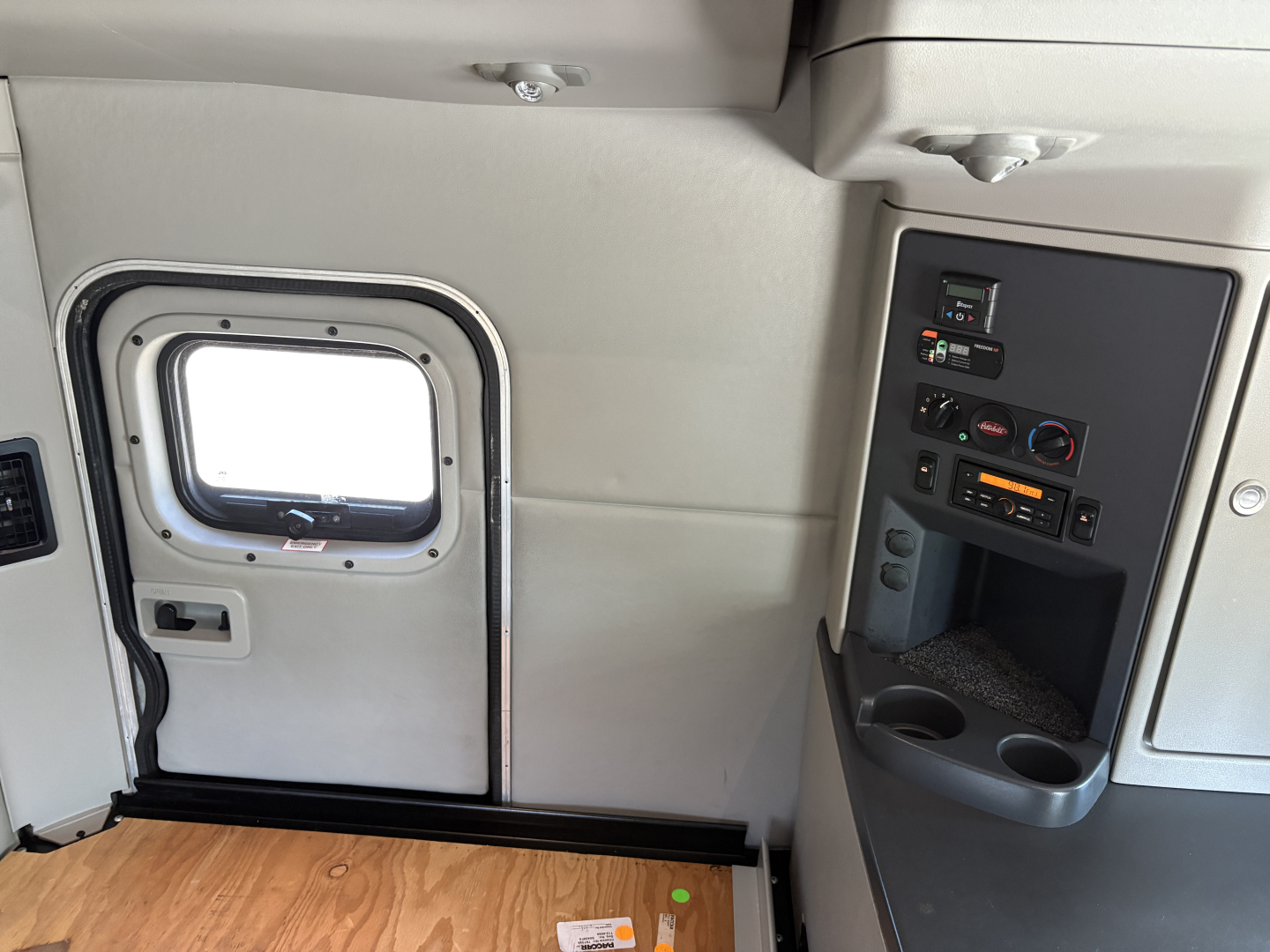 Peterbilt 579 truck cab interior scene showing side door with window and control panel in gray tones