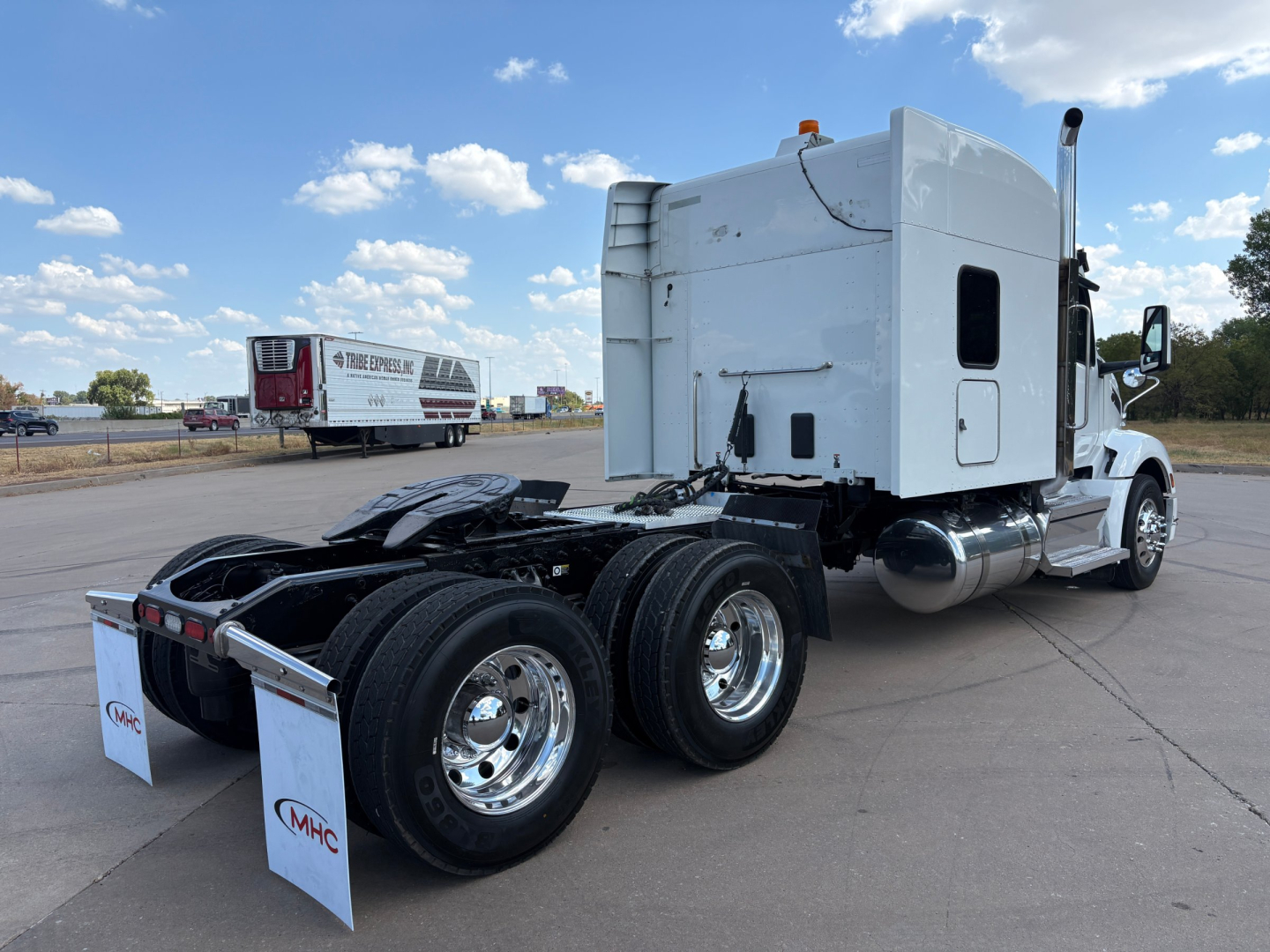 Peterbilt 579 tractor with sleeper cab, rear view showing dual rear axles and chrome wheels, white cab, fuel tanks, and fifth wheel plate; no legible markings visible in this view.
