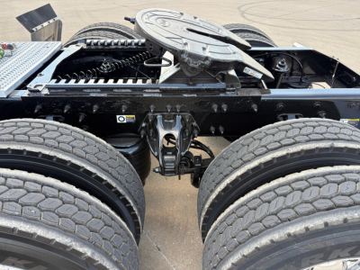 Peterbilt 579 chassis area showing fifth wheel, dual rear axles, and drivetrain components with warning labels.