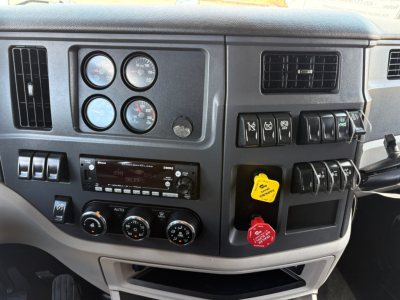 Peterbilt 579 dashboard and instrument cluster with gauges, control switches, and yellow and red keys in ignition area.