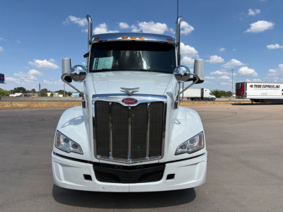 Peterbilt 579 tractor-view front showing large grille, headlights, side mirrors, and Peterbilt emblem; white exterior.