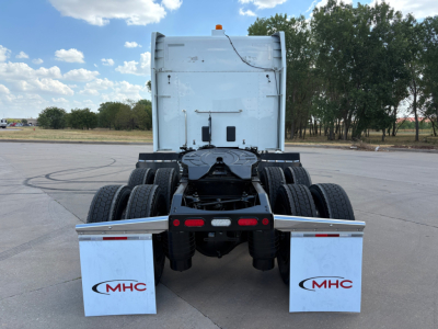 Peterbilt 579 rear view showing tandem axles and mud flaps with MHC logo.