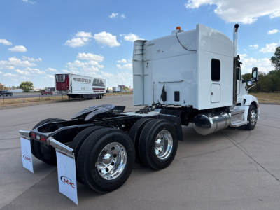 Peterbilt 579 tractor with sleeper cab, rear view showing dual rear axles and chrome wheels, white cab, fuel tanks, and fifth wheel plate; no legible markings visible in this view.